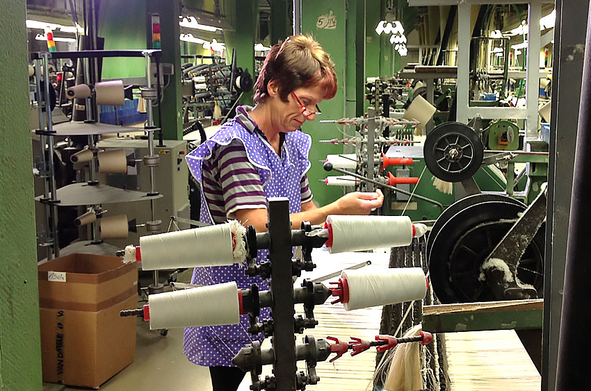 Experienced employee manually threads individual warp threads into the weaving machine