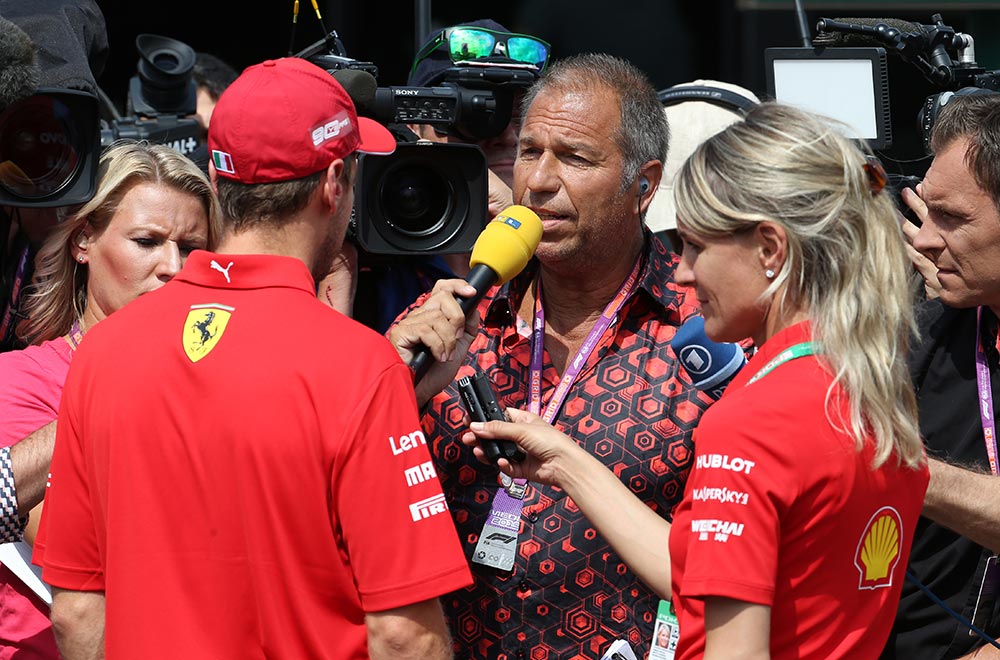 RTL-Moderator Kai Ebel trägt das GERMENS Hemd HEXAGON ZINNOBER während der Formel 1 in Hockenheim, Deutschland, 2019. Er ist im Interview mit Ferrari Rennfahrer Sebastian Vettel. Hemdkünstler: René König, Foto: Russel Batchelor