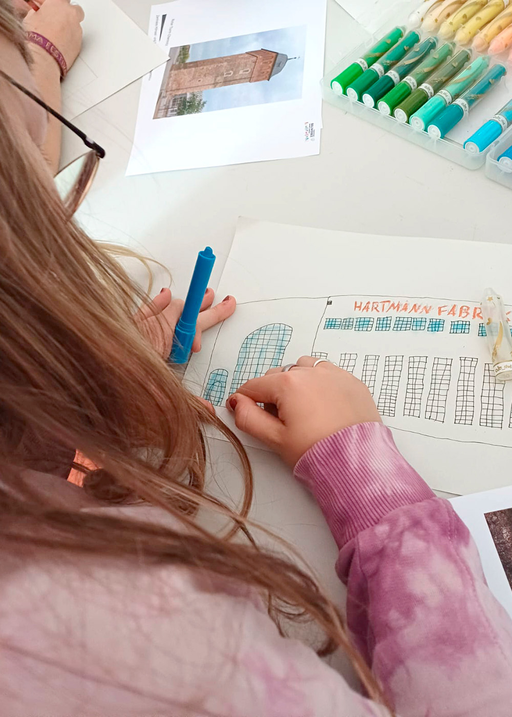 Una niña pinta la fábrica Hartmann a partir de una foto, como parte del proyecto «Los edificios de Chemnitz se convierten en obras de arte que se pueden llevar encima»