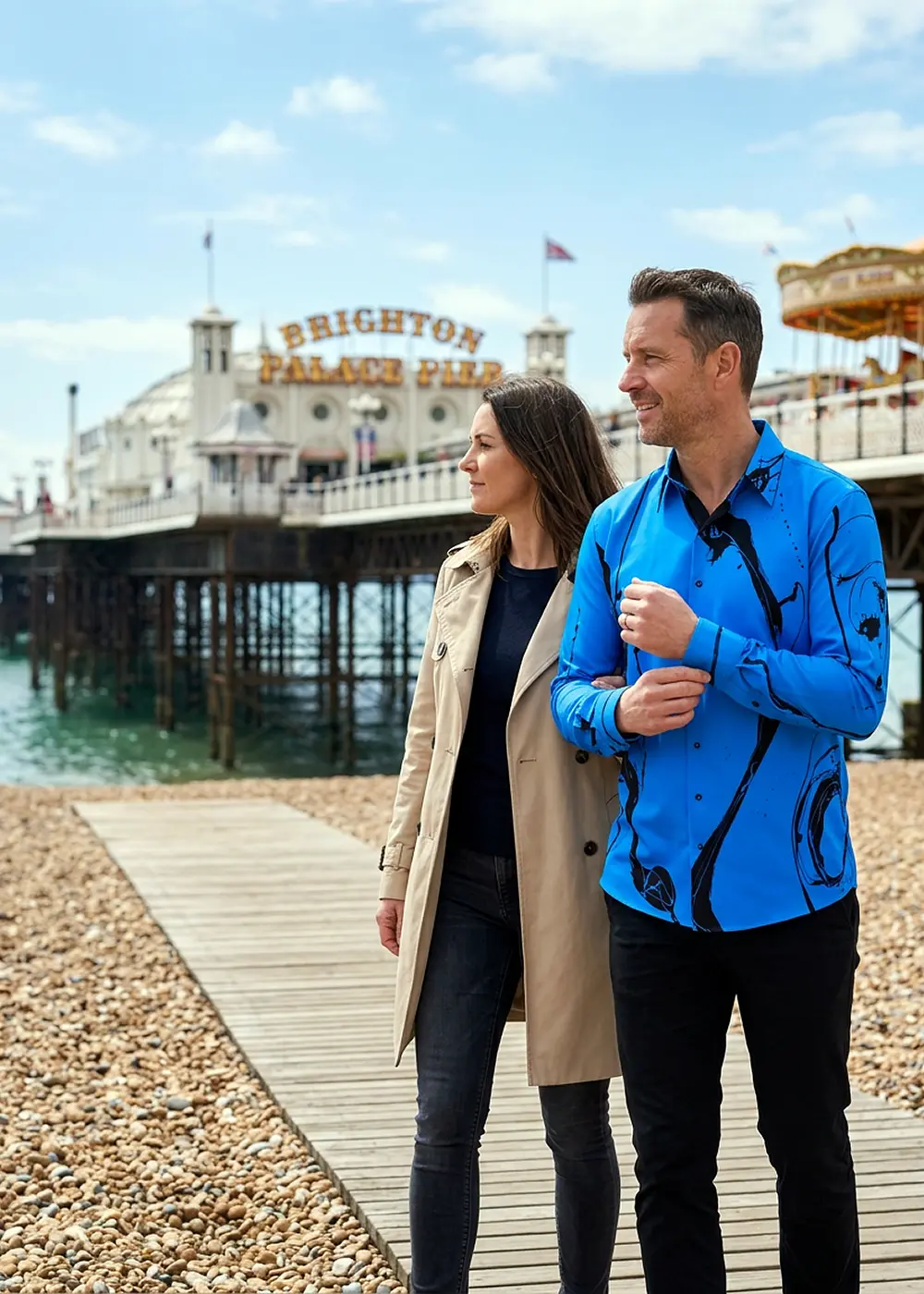 Ein Ehepaar ist zu Besuch in Brighton am Strand. Der Mann trägt das blaue GERMENS Hemd LEBENSADER MARINE.