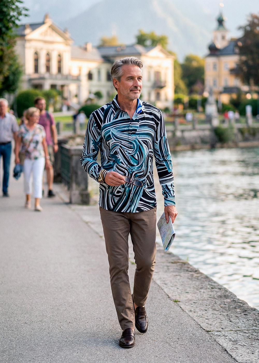 Ein Mann spaziert am Wasser von Bad Ischl. Er trägt das schwarz-blaue Hemd BRUSHSTROKE von GERMENS.