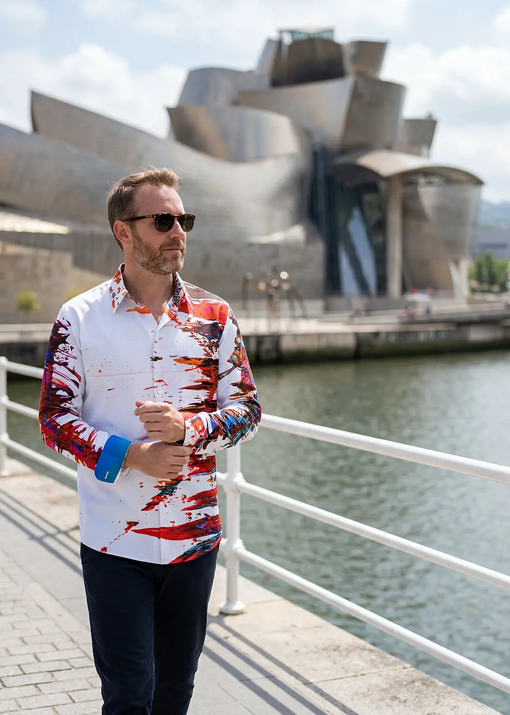 Ein Tourist besucht die spanische Stadt Bilbao. Er trägt das GERMENS hemd INTERFERENCE. Im Hintergrund ist das Guggenheim-Museum Bilbao zu sehen.
