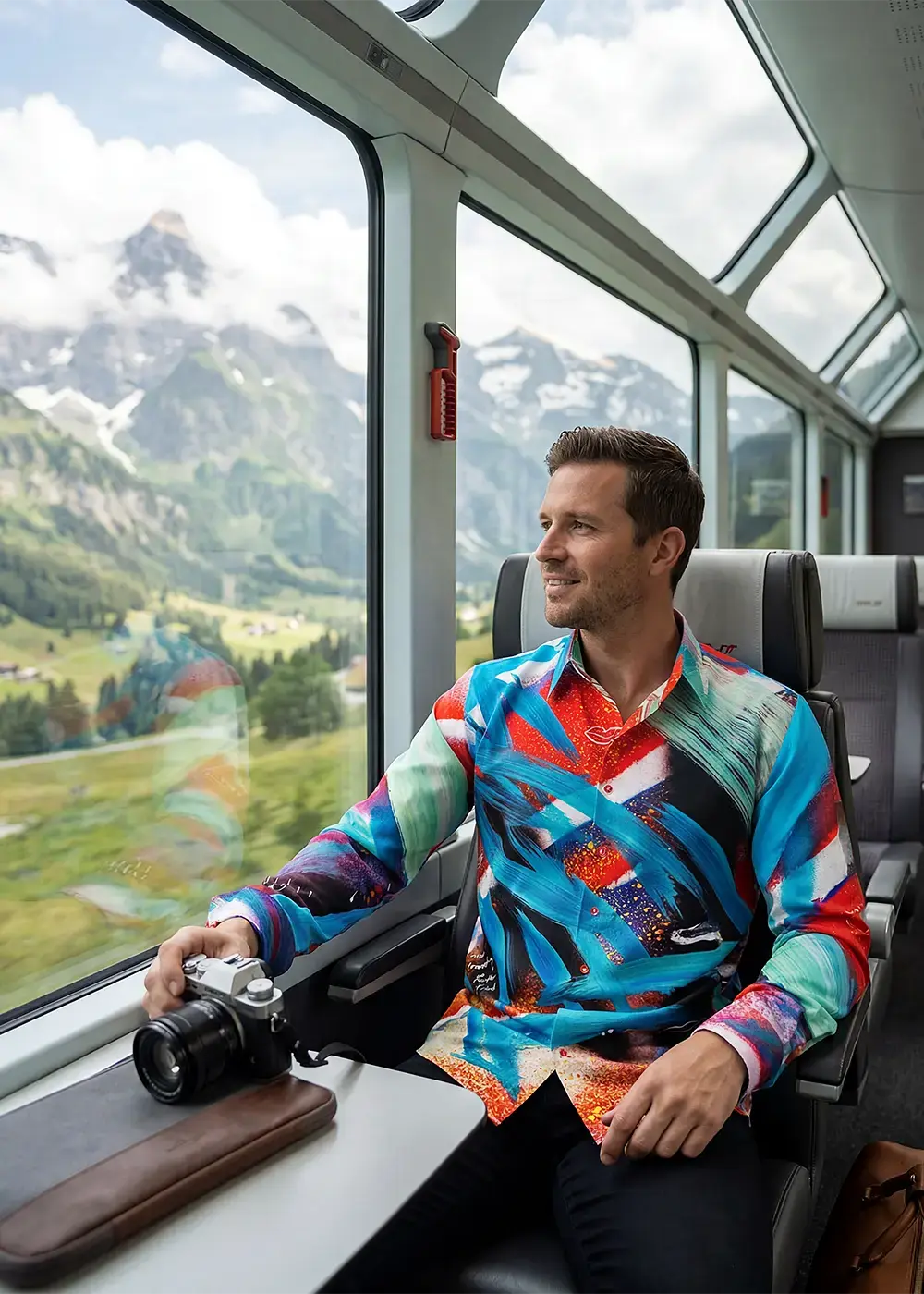 A passenger travels through the Swiss Alps on a panoramic train. He is wearing the GERMENS shirt THE TIME TRAVELING.