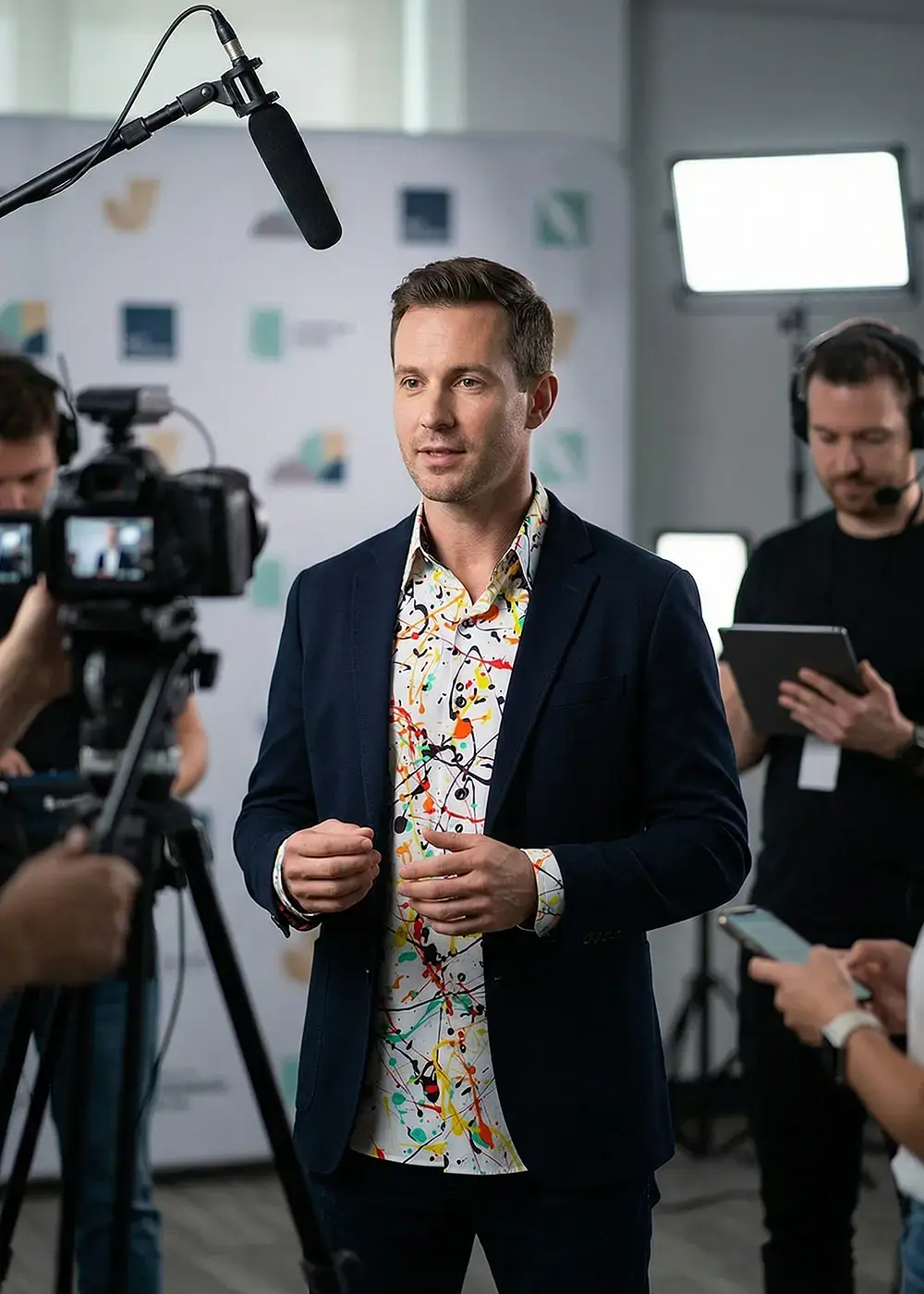 Recording for a social media post. The speaker is wearing a suit with the GERMENS FRISKY shirt underneath.