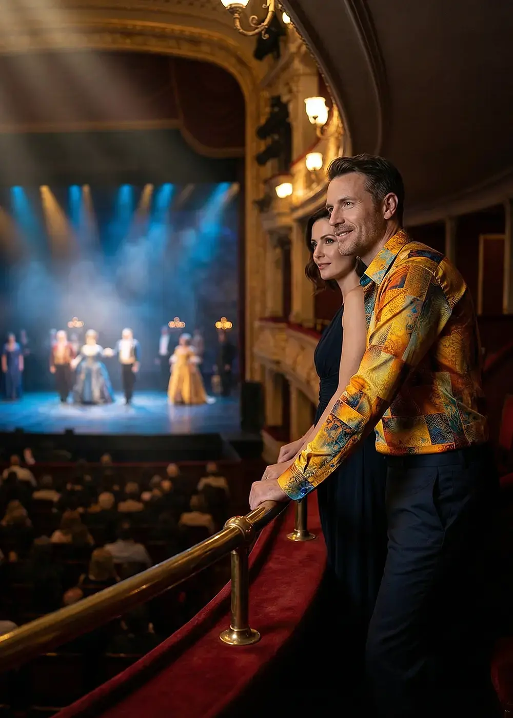 A couple is in a box at the opera. The man is wearing the GERMENS Draco Gold shirt.