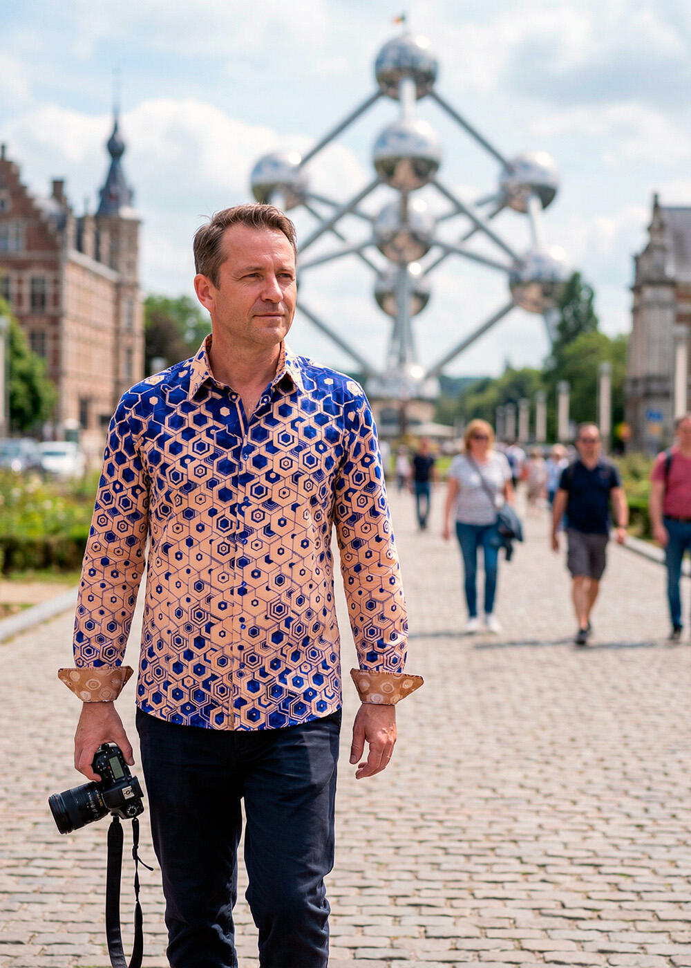 A man wearing a colorful GERMENS Hexagon Calcit shirt in Brussels near the Atomium