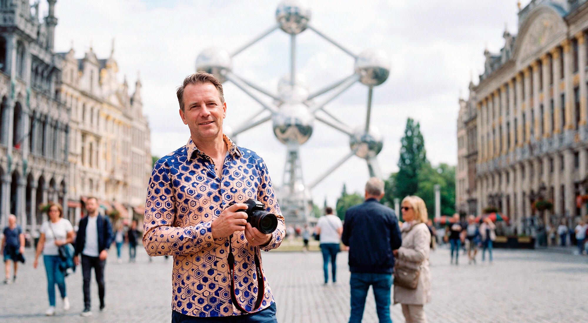 A man wearing a colorful GERMENS Hexagon Calcit shirt in Brussels near the Atomium