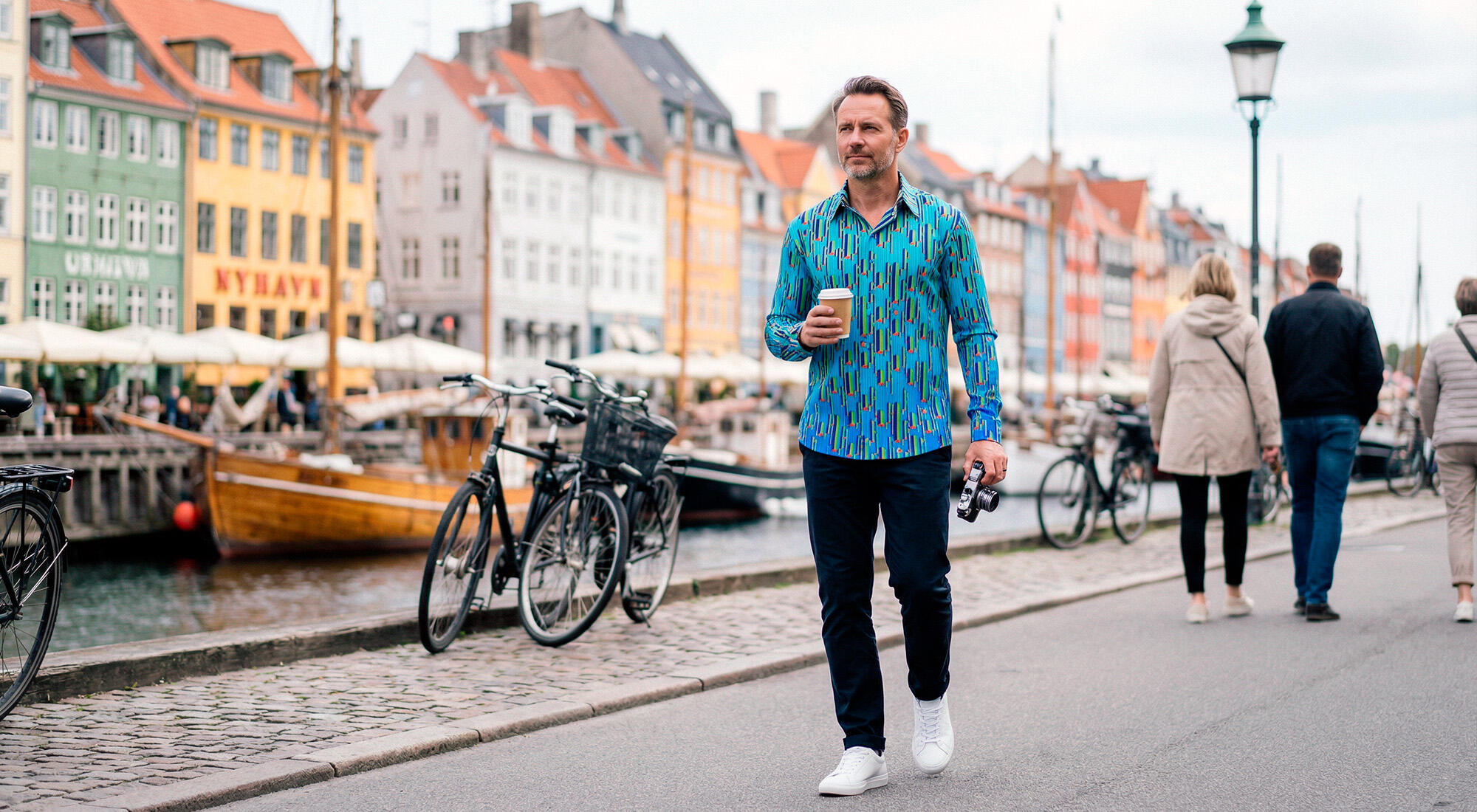 Ein Mann ist unterwegs in der dänischen Stadt Kopenhagen. Er trägt das blaue Langarmhemd STALACNITE BLUE von GERMENS artfashion aus Chemnitz.