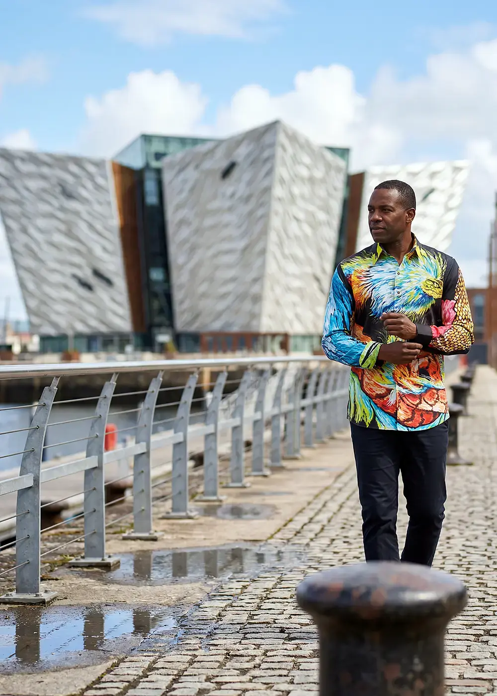 A tourist strolls through Belfast in Great Britain. He is wearing the colorful QUETZAL shirt from GERMENS.