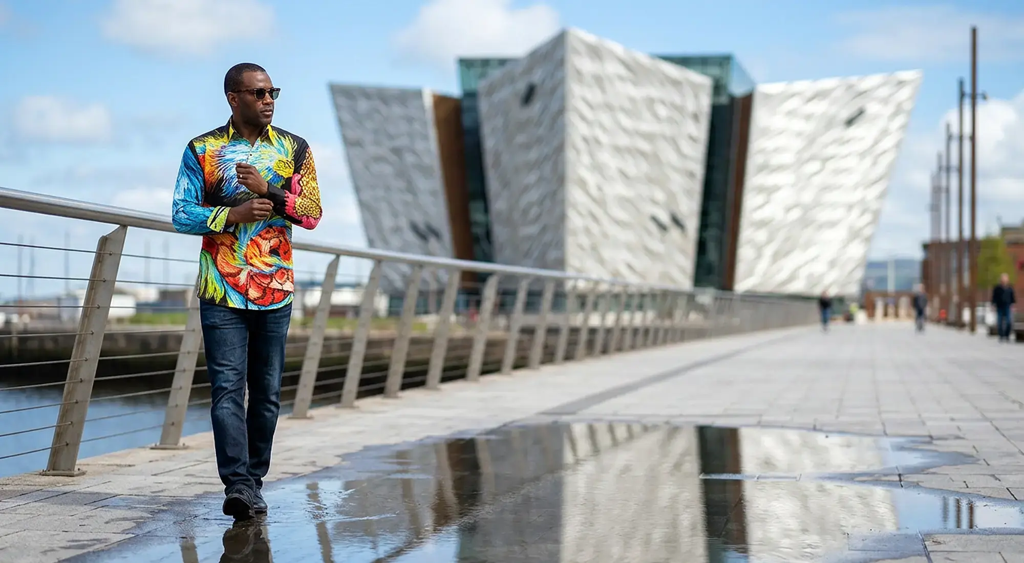 A tourist strolls through Belfast in Great Britain. He is wearing the colorful QUETZAL shirt from GERMENS.