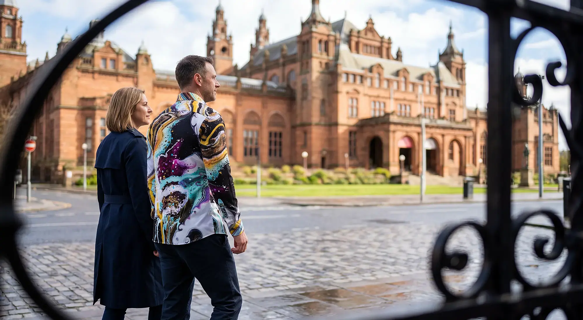 A married couple is visiting the city of Glasgow. The man is wearing the colorful JAWS OF MAUI shirt by GERMENS.