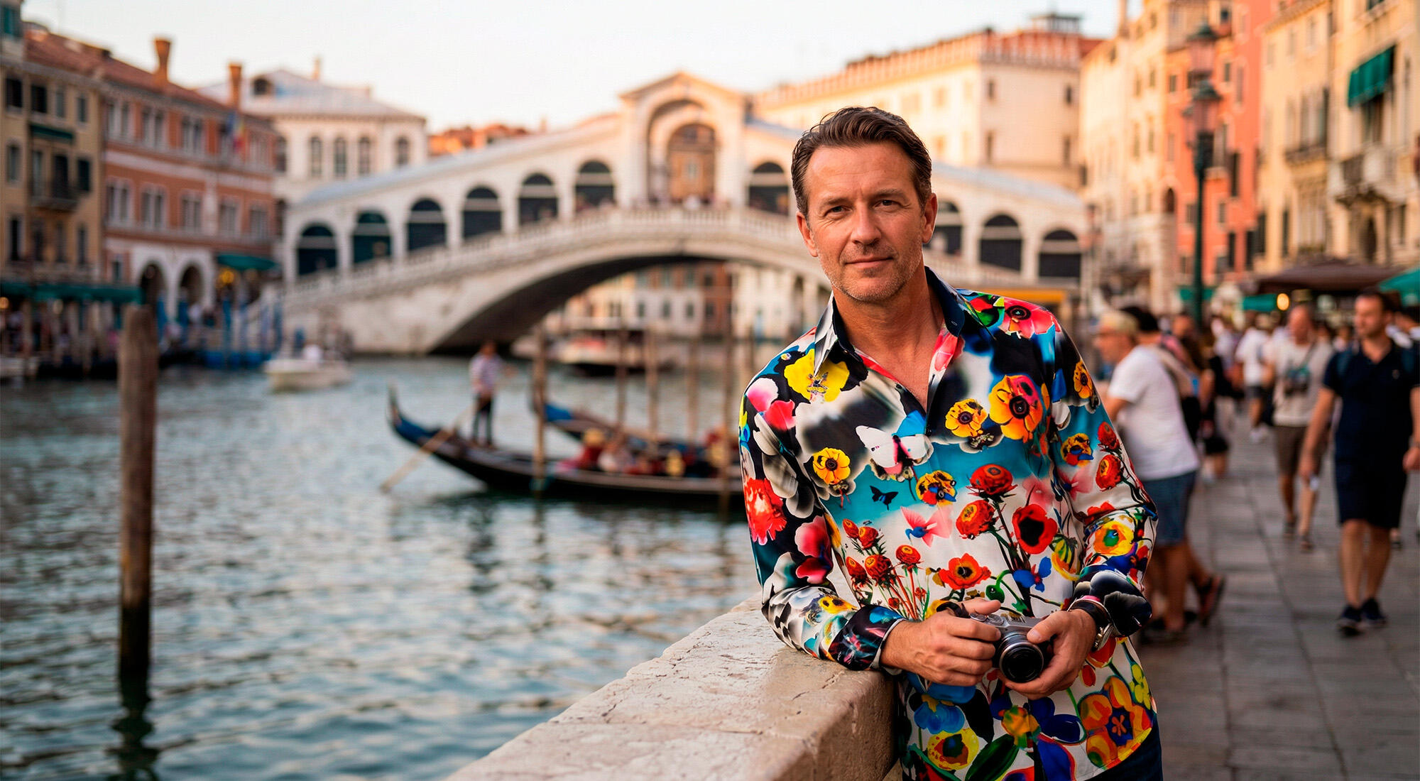 A man stands on the Grand Canal in Venice in front of the Rialto Bridge wearing the colorful FLOWERDREAM shirt by GERMENS artfashion.
