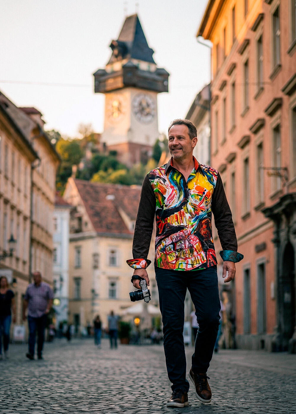 A man walks through the city of Graz wearing the eye-catching MEMENTO MASKARA shirt by GERMENS.