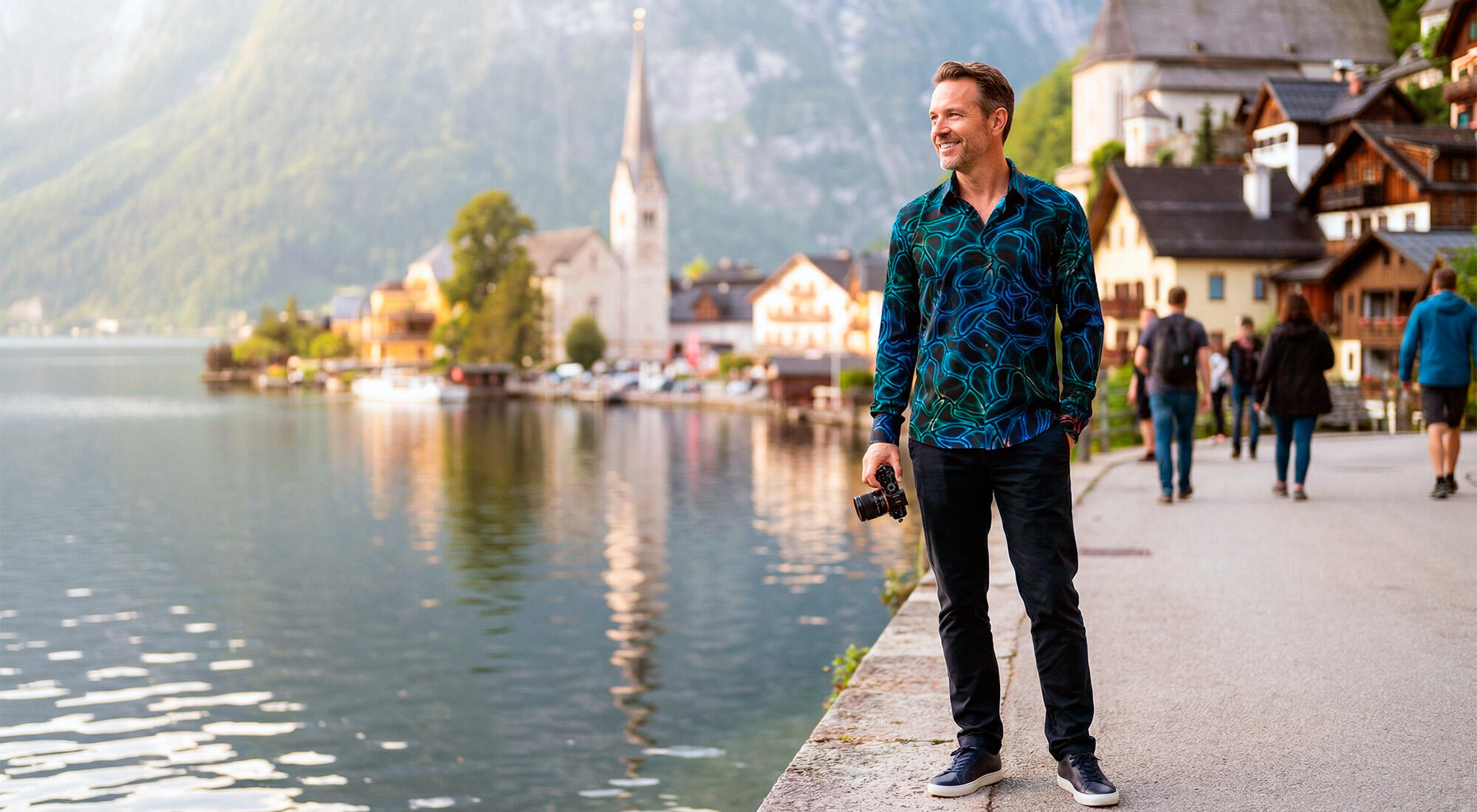 A tourist walks along the shore of Lake Hallstatt. He is wearing the black and blue NETWORK MIRAKEL shirt by GERMENS.