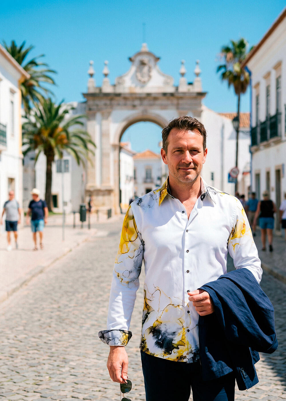 A man walks down a street in the Portuguese city of Faro wearing the white NEBULA shirt by GERMENS.
