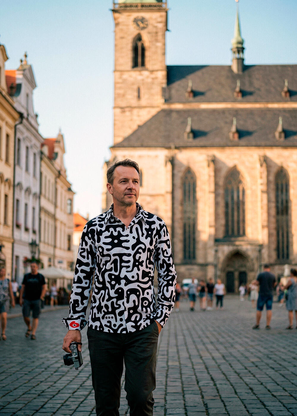 A man walks through the Czech city of Pilsen wearing the black and white GERMENS JUPPI shirt.